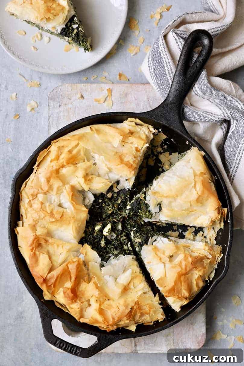 Photo of Skillet Spanakopita (Greek Spinach and Feta Pie) cast iron skillet with gray striped towel.