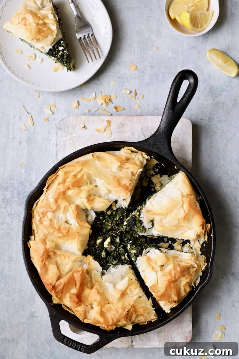 Photo of Skillet Spanakopita (Greek Spinach and Feta Pie) with a piece removed to a plate.