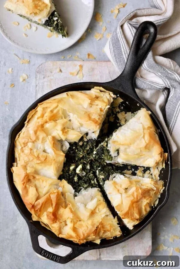 Skillet Spanakopita (Greek Spinach and Feta Pie) - Overhead shot in cast iron skillet with gray striped towel