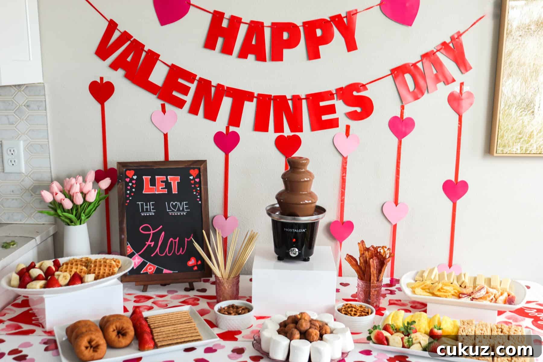 Valentine's Day chocolate fountain bar set up with a table full of dippers.
