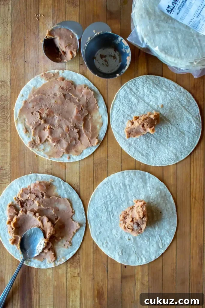 Refried beans being spread on corn tortillas to make Huevos Rancheros. 