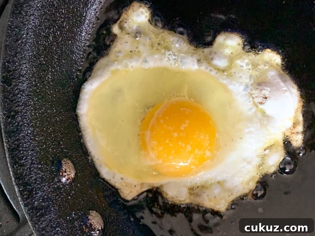 An egg frying in a black skillet for Huevos Rancheros 