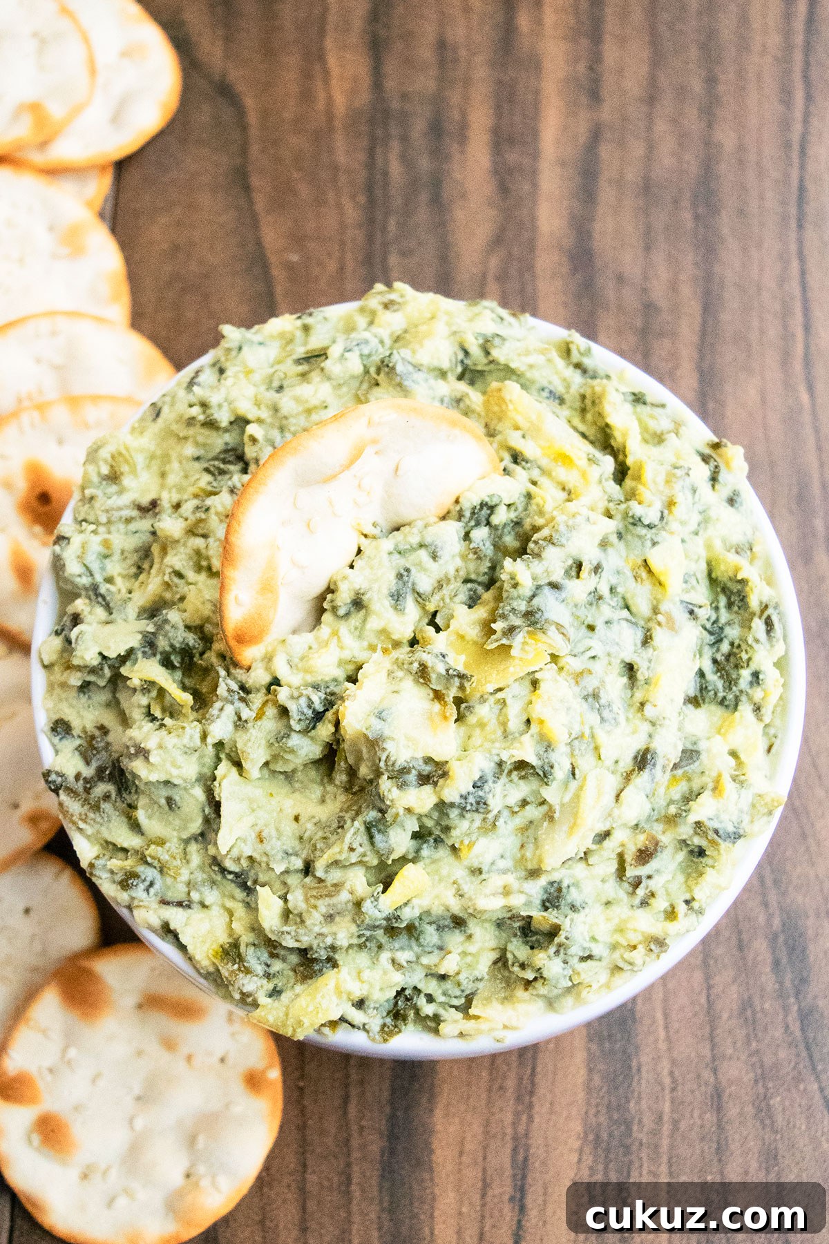 Creamy One‑Bowl Spinach and Artichoke Dip Recipe 2 Easy homemade spinach artichoke dip in white bowl with crackers.