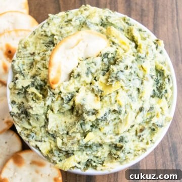 Creamy One‑Bowl Spinach and Artichoke Dip Recipe 6 Best easy homemade creamy spinach artichoke dip in white bowl with round crackers.