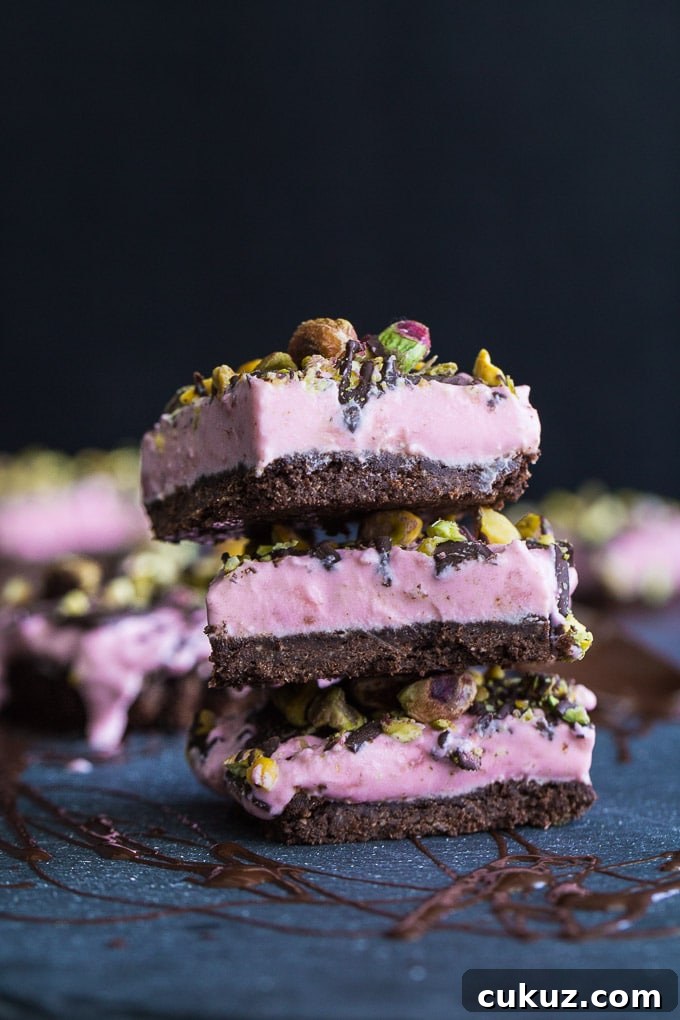 Up-close view of a stack of Frozen Strawberry Goat Cheese Bars on a dark surface with a dark background.