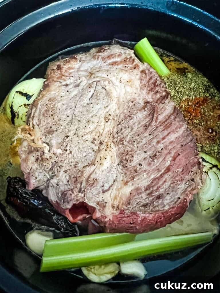 Birria Tacos Recipe with Dipping Consomme 4 beef, vegetables, chilis and broth in the dutch oven ready for braising.