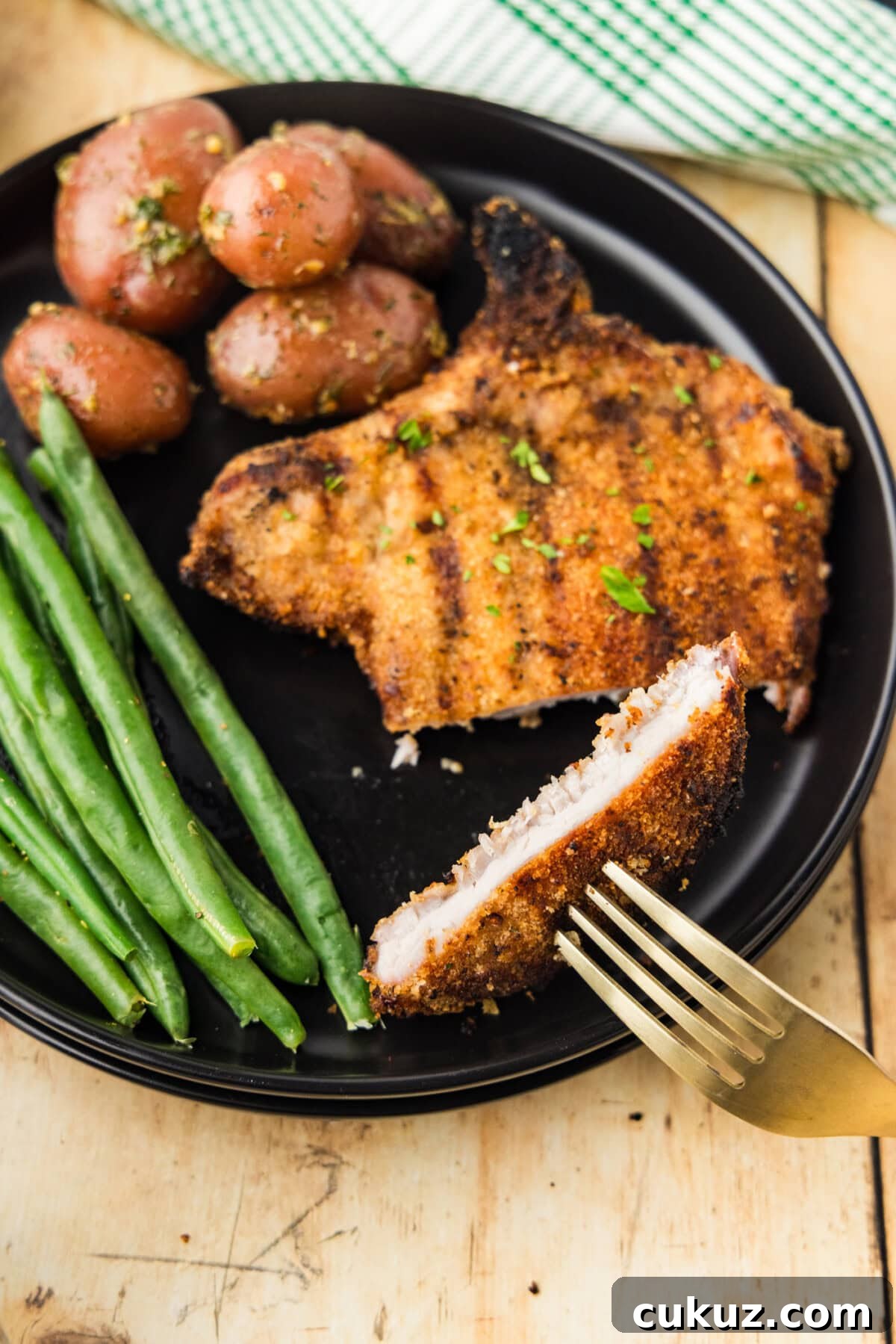 Crispy Grilled Breaded Pork Chops Recipe 11 Grilled Breaded Pork Chop on plate with green beans and potatoes and fork lifting a slice