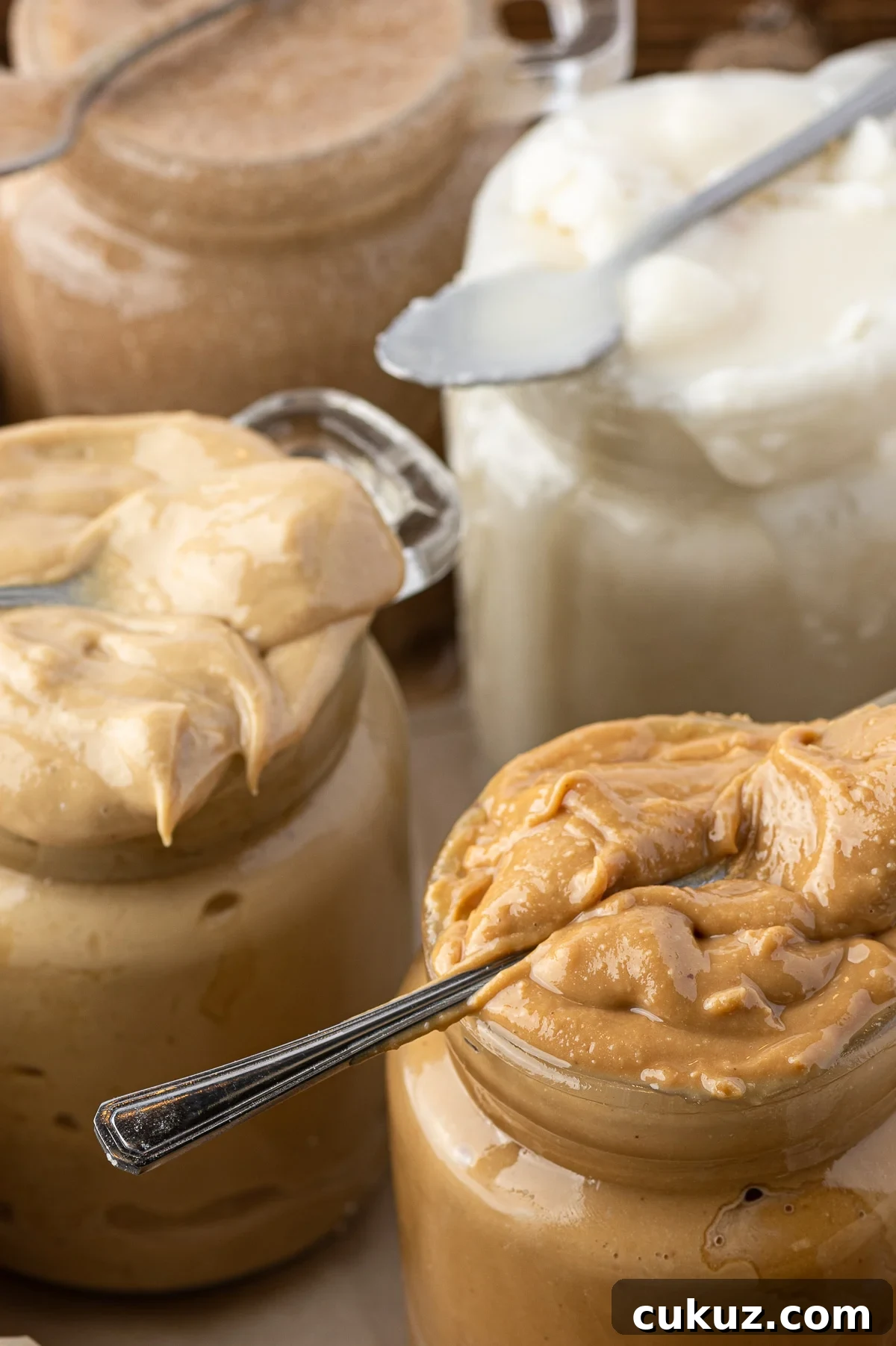 Jars of different nut butters overflowing from their glass jars