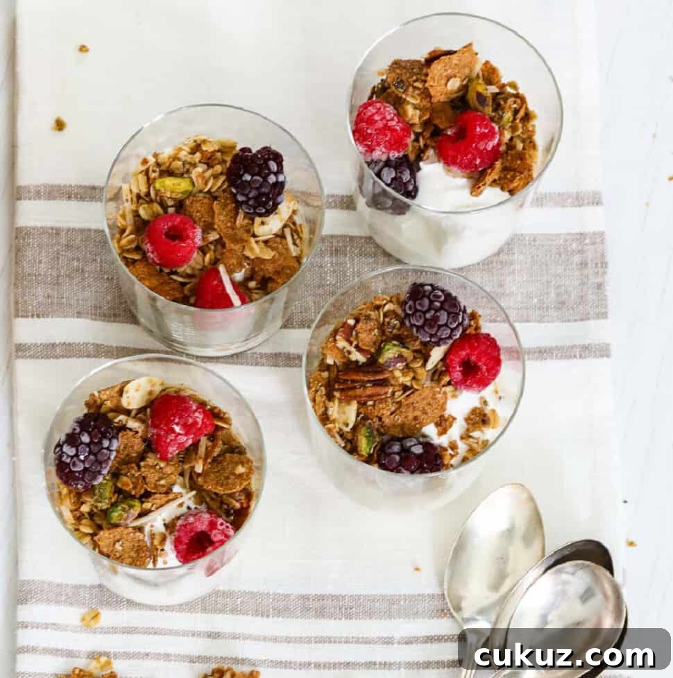 Four small yogurt parfaits made with yogurt, granola and berries.