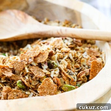A wooden bowl filled with granola and a wooden spoon.