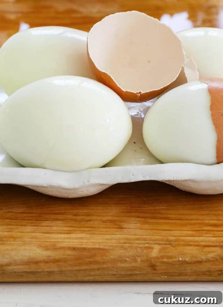 6 perfectly hard boiled eggs with a cracked half of an egg shelf on top.