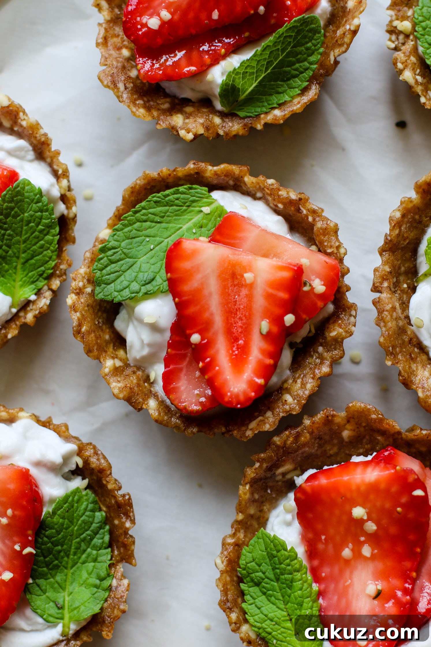 No-Bake Strawberries 'N' Cream Tarts served on a plate with fresh mint and hemp hearts by Flora & Vino