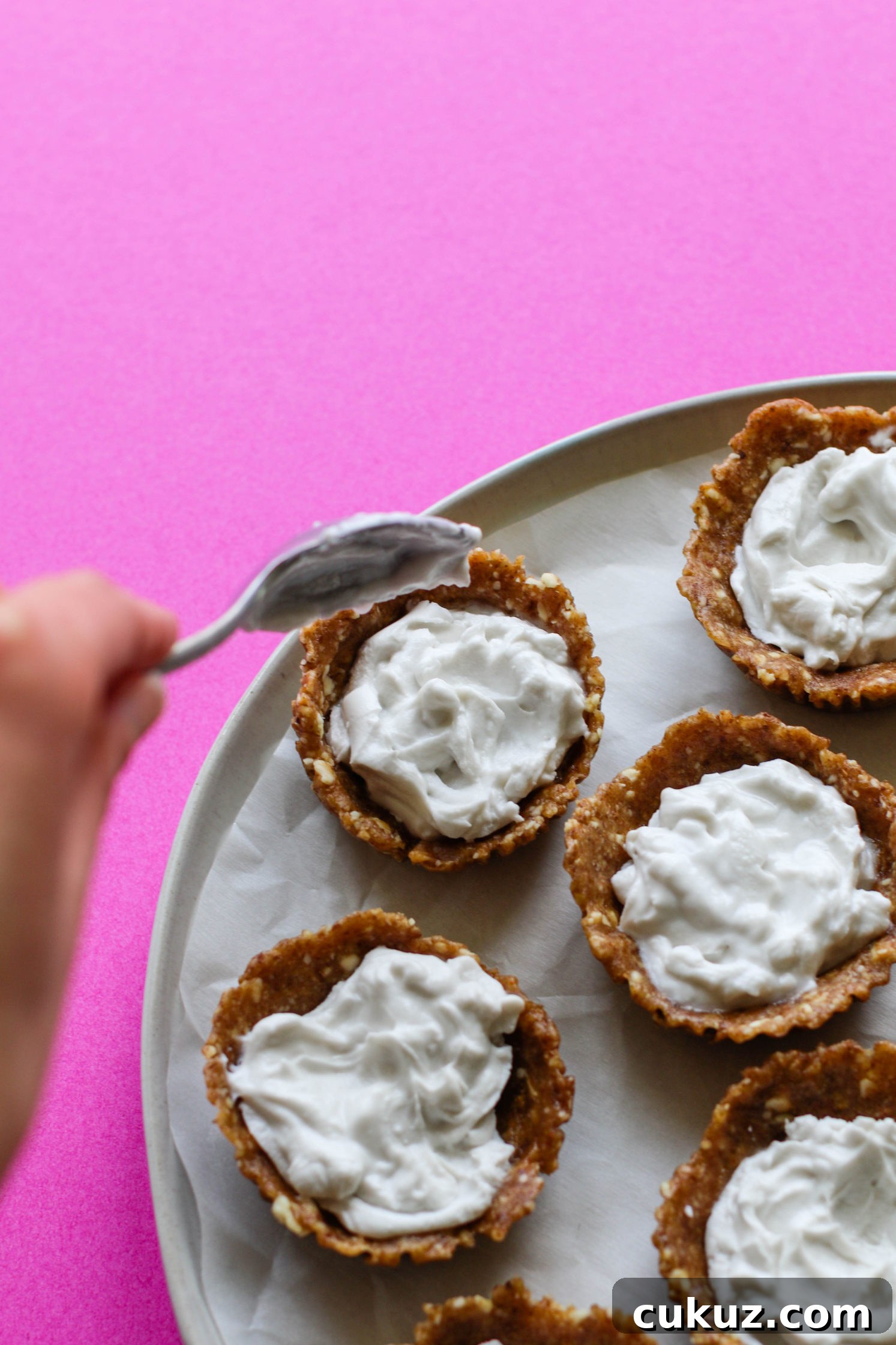 hand adding spoonful of coconut cream to no-bake tarts by Flora & Vino