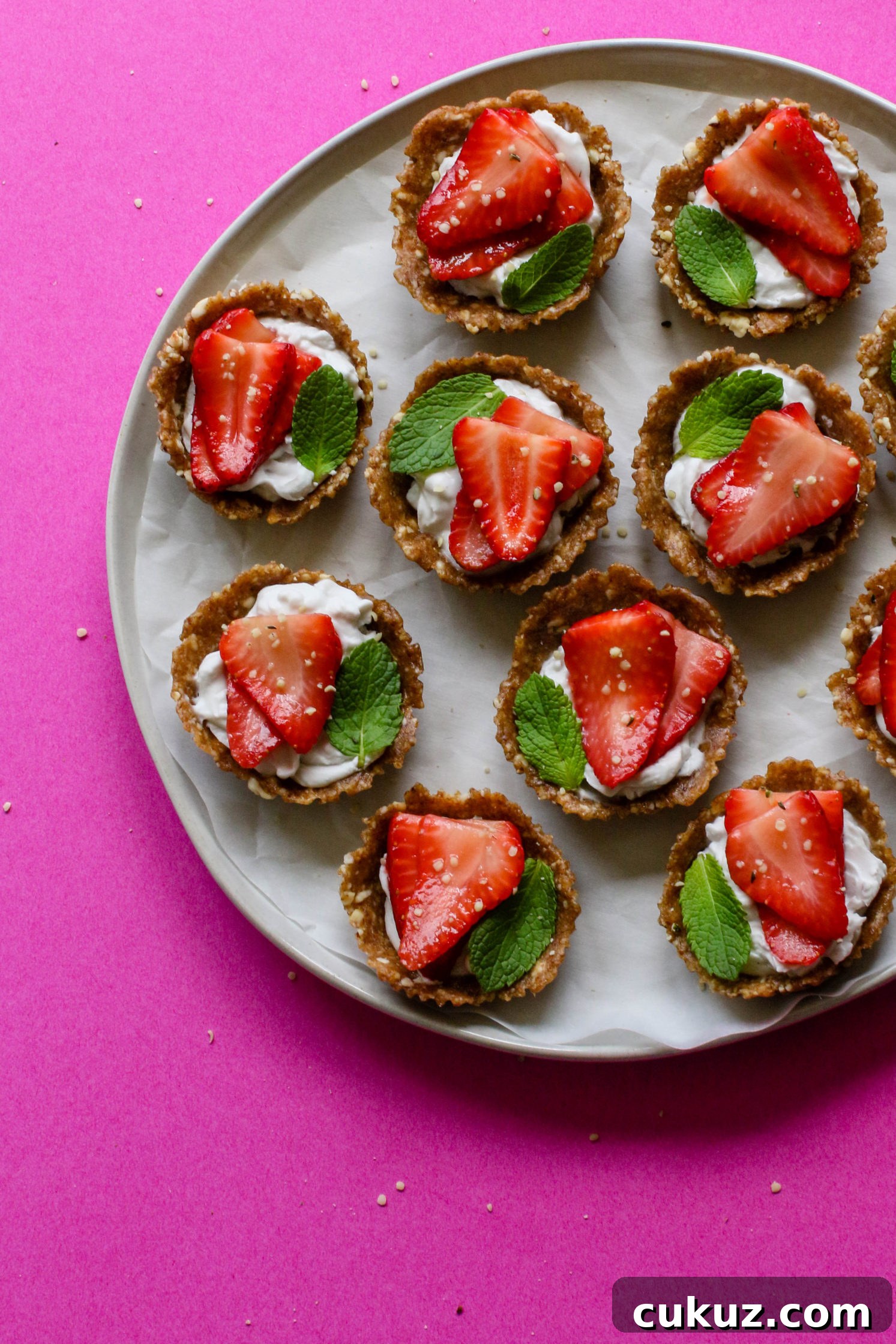 No-Bake Strawberries 'N' Cream Tarts served on a plate with fresh mint and hemp hearts by Flora & Vino