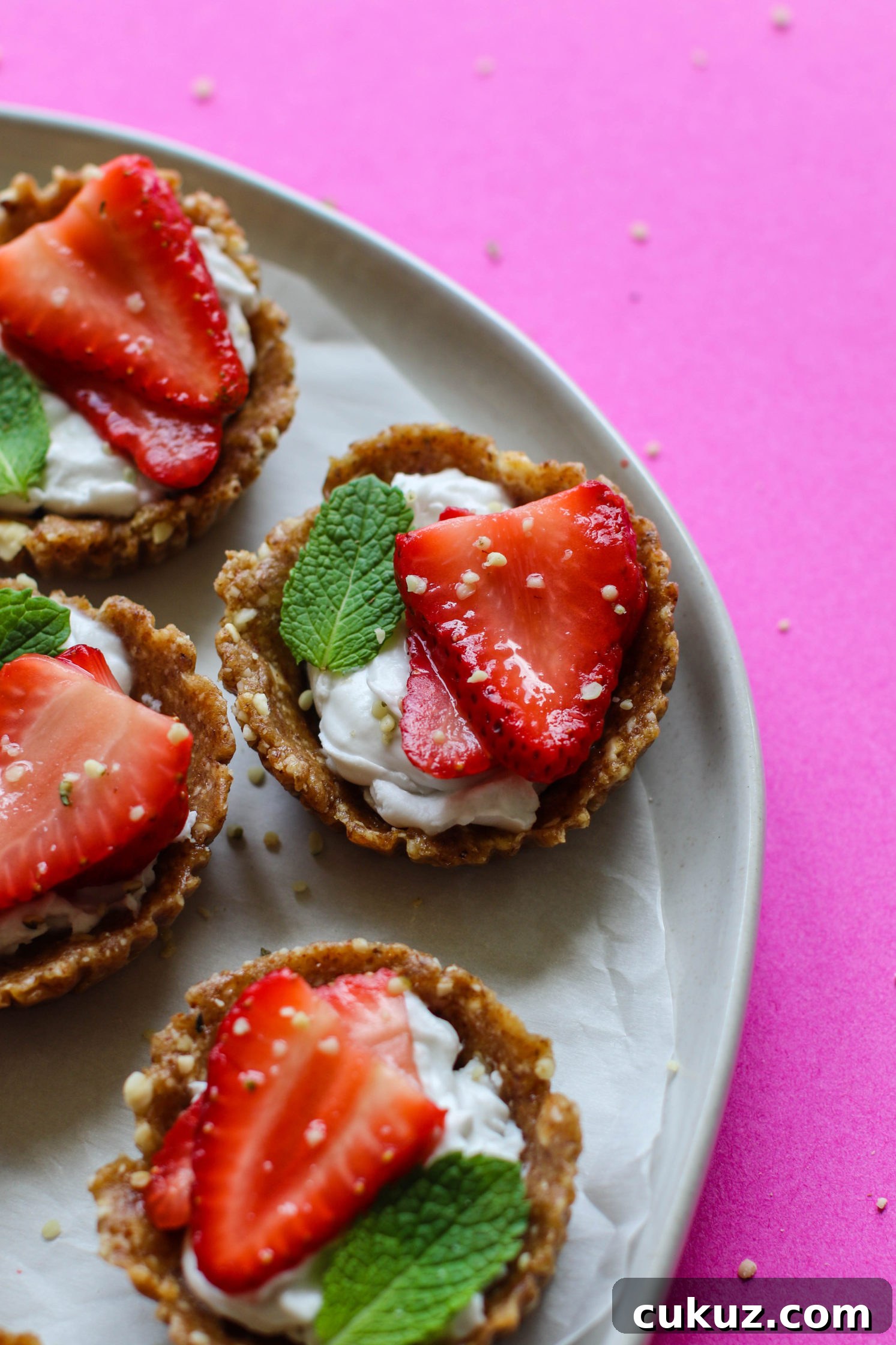 No-Bake Strawberries 'N' Cream Tarts served on a plate with fresh mint and hemp hearts by Flora & Vino