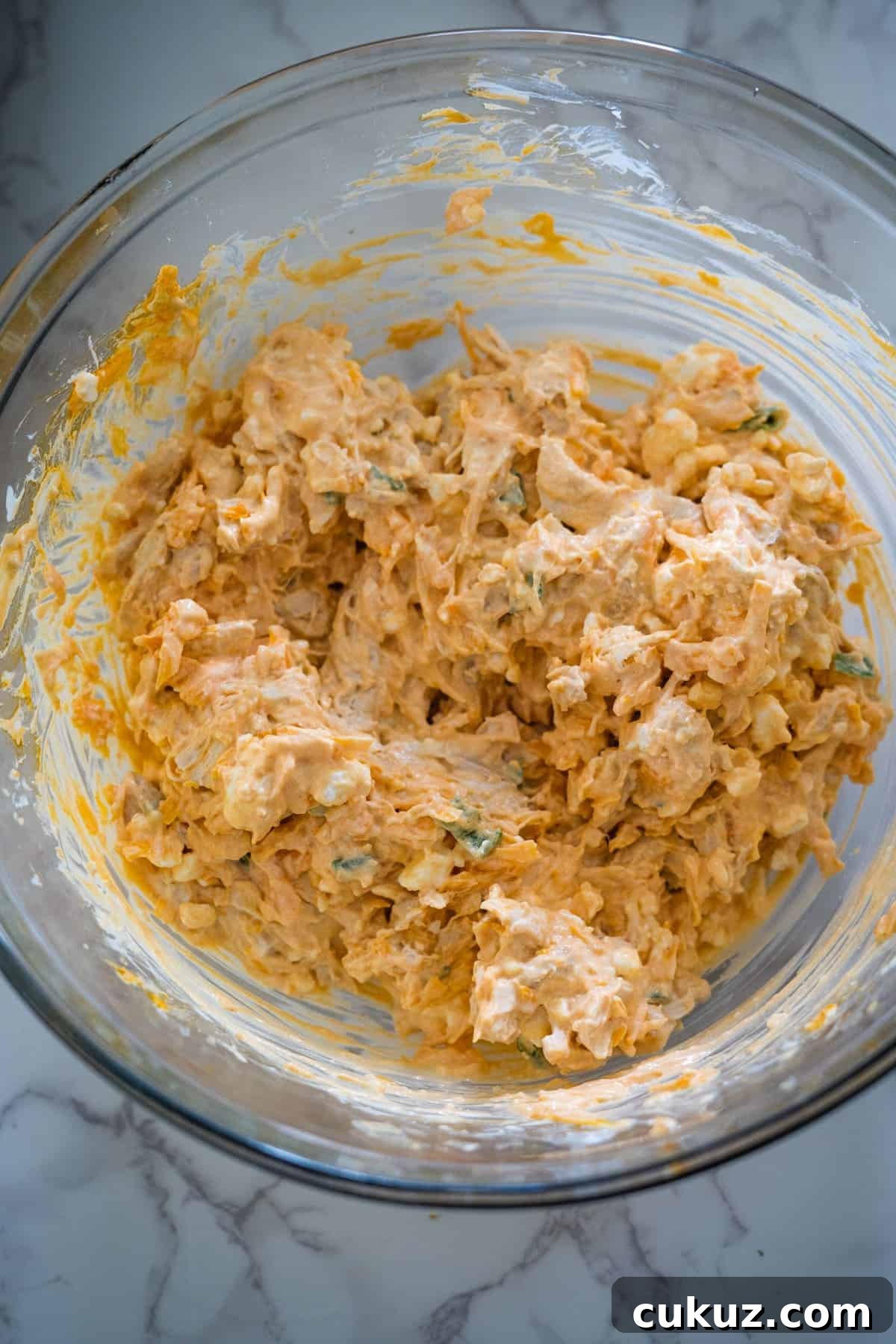 A bowl filled with a mixture of cottage cheese and buffalo chicken dip.