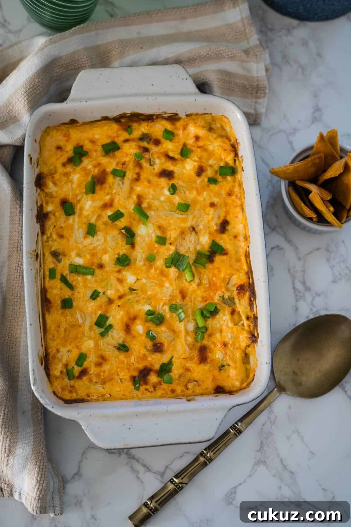 Cheesy buffalo chicken tater tot dip in a white dish.