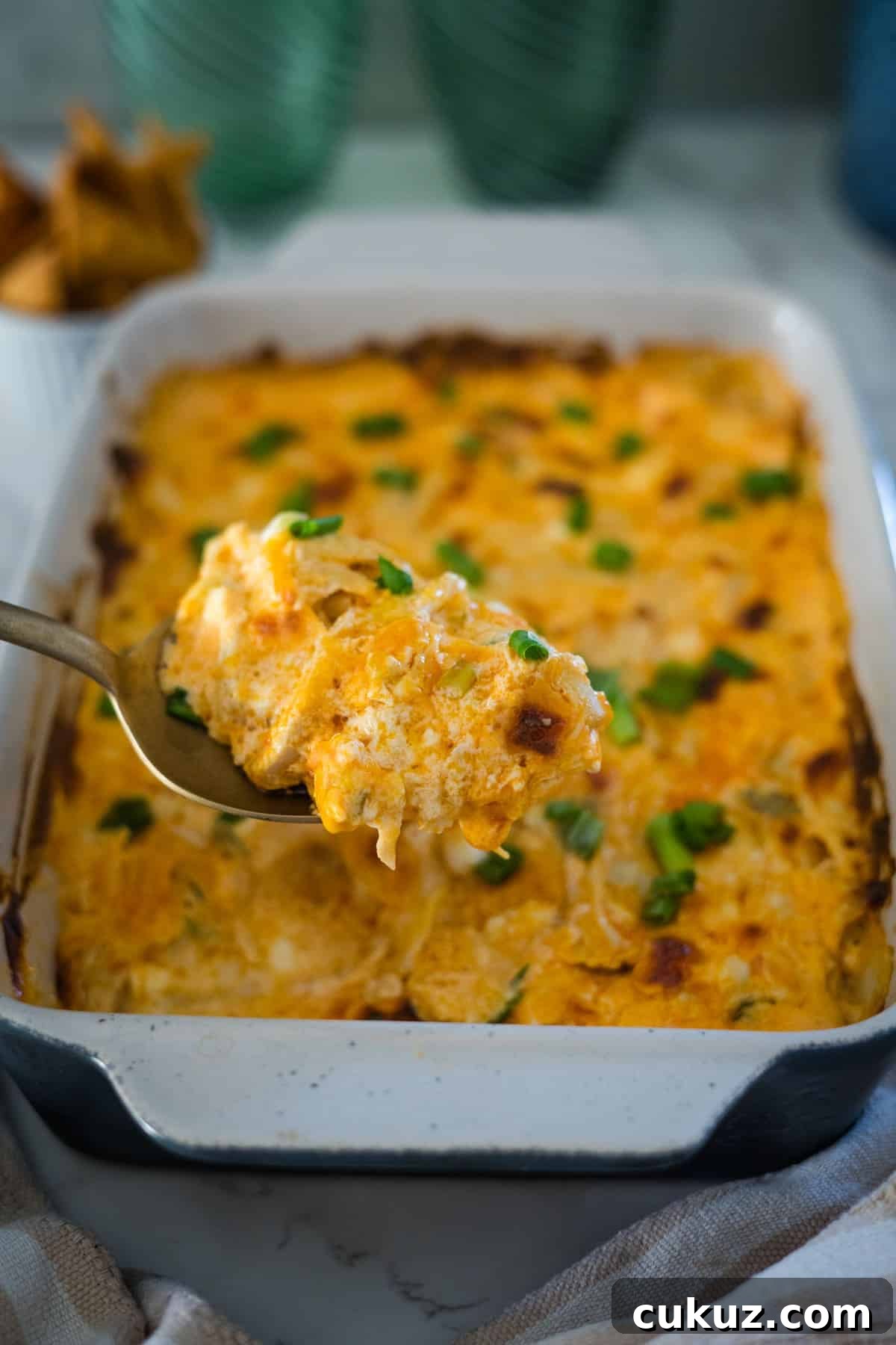 Cheesy buffalo chicken dip in a baking dish with a spoon.