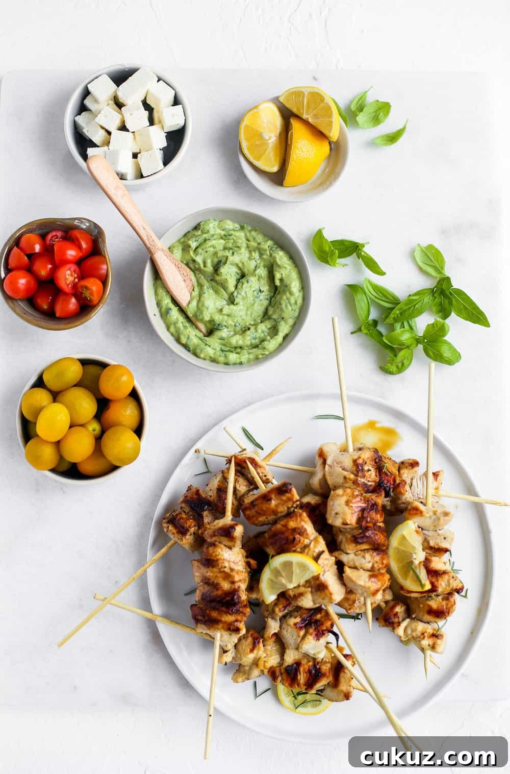 Lemon Garlic Chicken Skewer Bowls with green goddess dressing, tomatoes, feta, and lemons in a white bowl