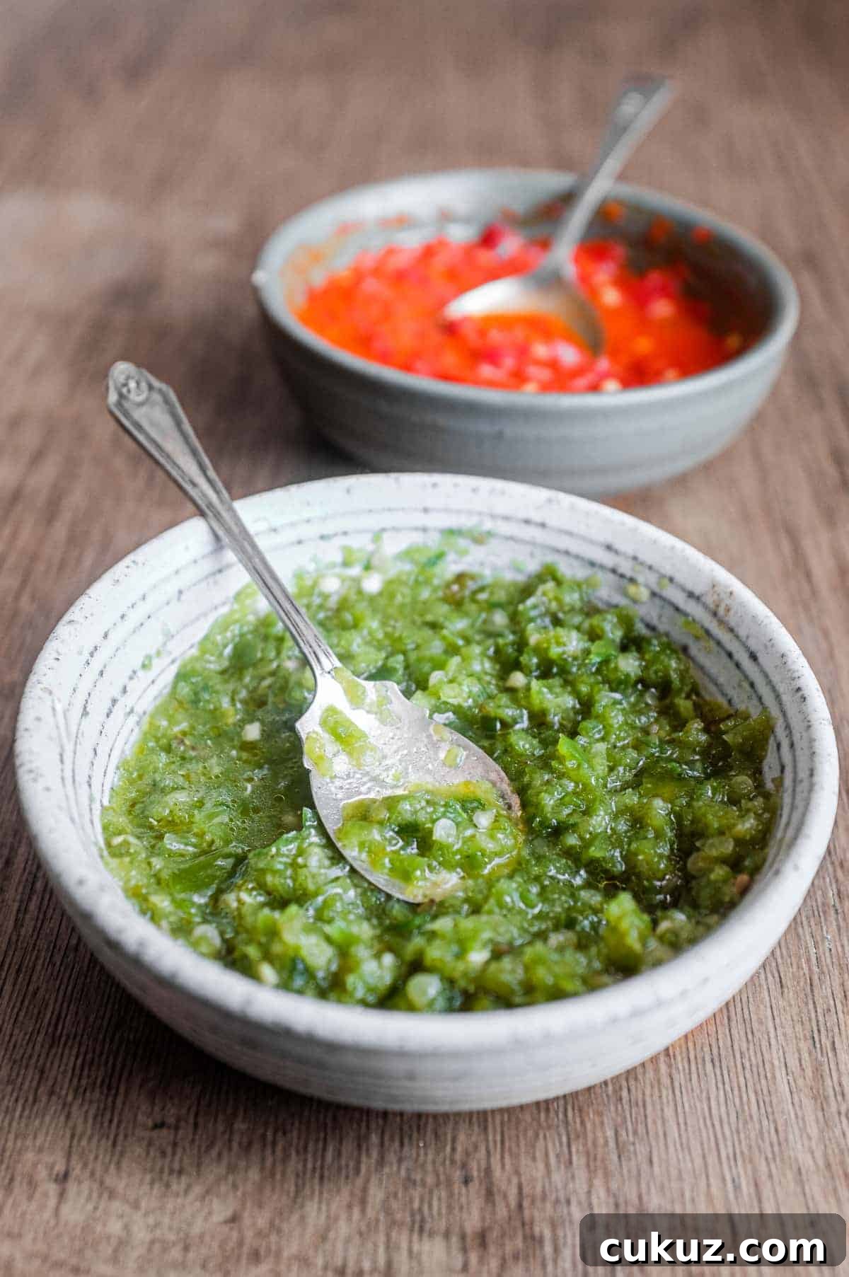 Two bowls of Middle Eastern Shatta Sauce. A green sauce sits in the foreground with a red sauce in the background.