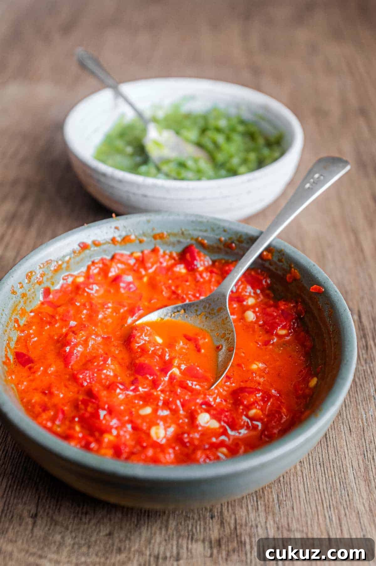 Two bowls of Middle Eastern Shatta Sauce. A red sauce sits in the foreground with a green sauce in the background.
