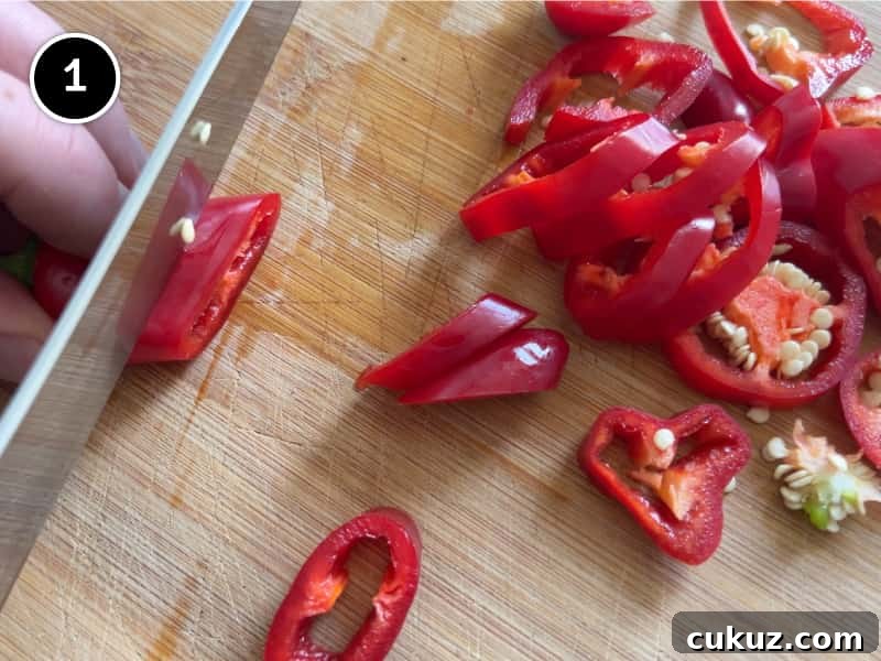 Chopping red chillies on a board into slices.