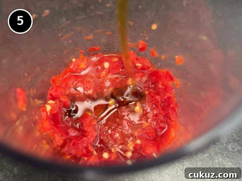 Mixing oil and vinegar into a jug of Middle Eastern Red Shatta sauce.
