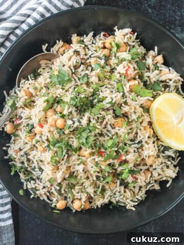 Spinach rice and chickpeas in a black serving bowl topped with a lemon wedge.