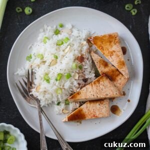 Coconut rice on a plate with triangles of baked tofu and two forks.
