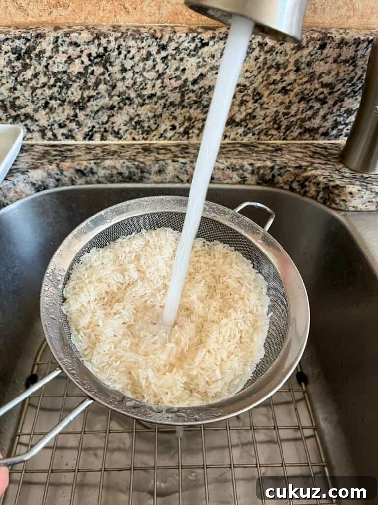 Rinsing rice in a fine mesh strainer with water.