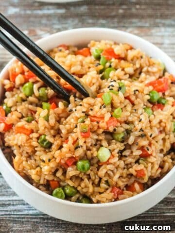 Chopsticks in a bowl of vegan fried rice.