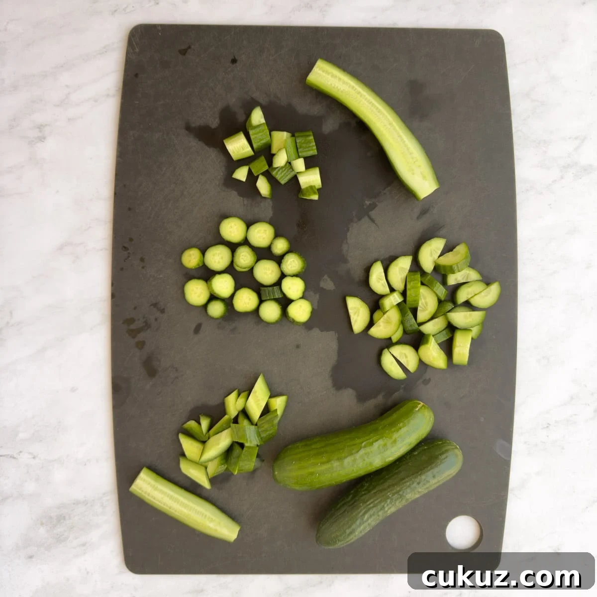 Cucumbers on a black cutting board cut in different ways.