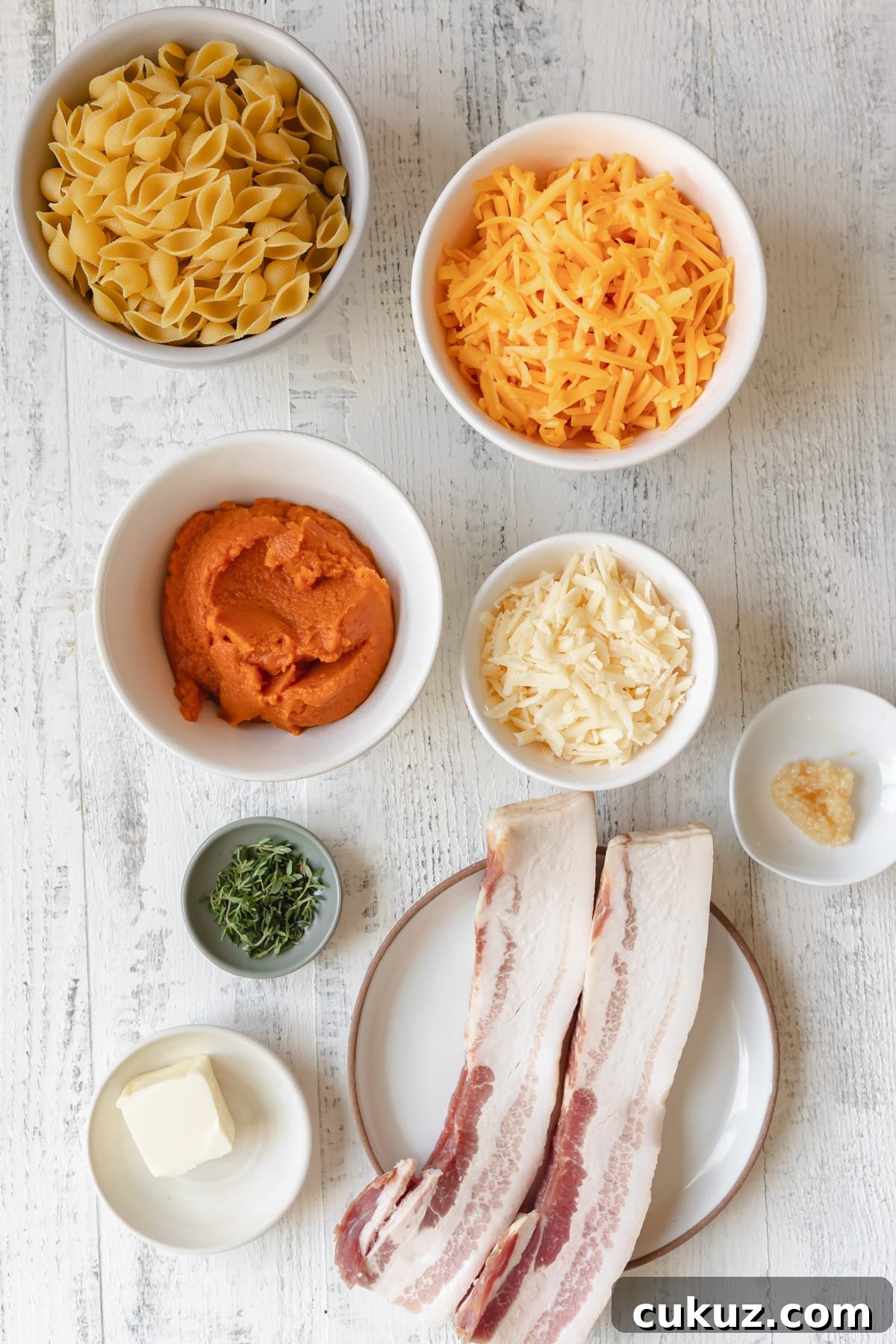 ingredients in small dishes needed to make a macaroni and cheese recipe with bacon and pumpkin. 