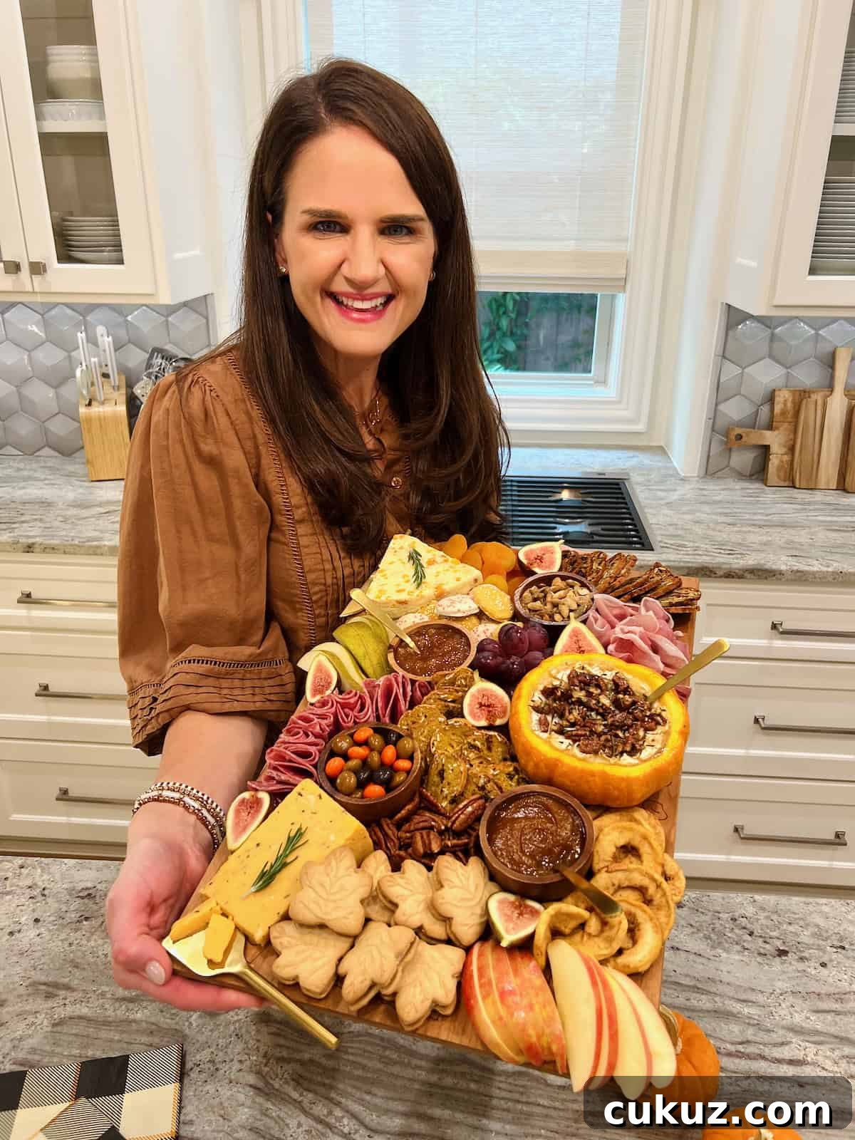 Maegan Brown wearing a brown three quarter length sleeved blouse holding her fall signature board.