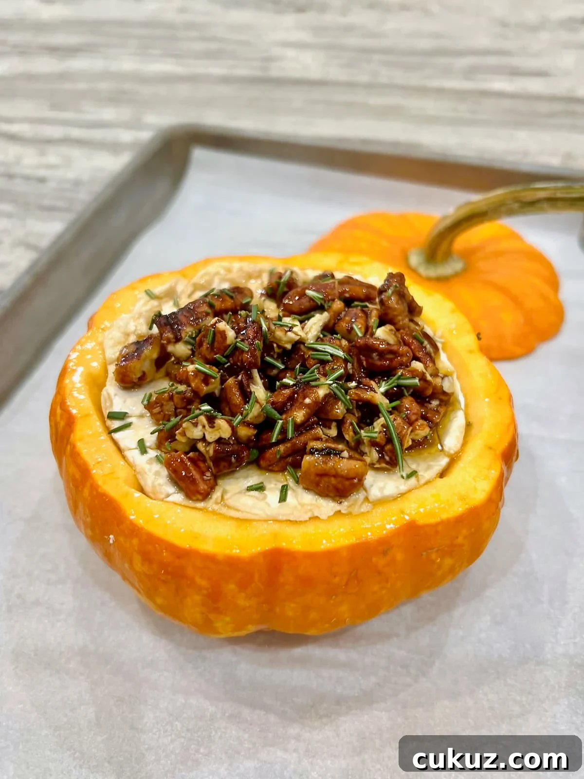 Pumpkin baked brie on a parchment lined baking sheet.