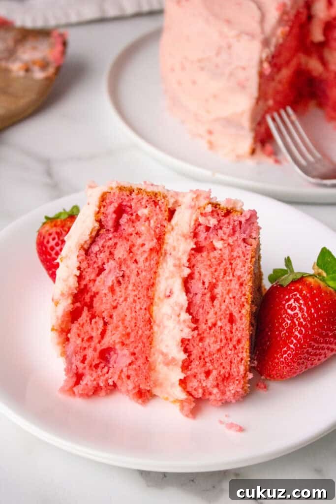piece of strawberry cake on a plate with a strawberry
