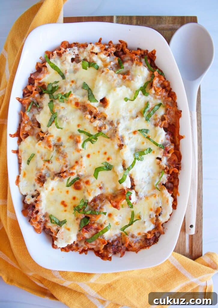 Deconstructed lasagna topped with golden brown melted cheese and shredded basil in a white casserole dish.