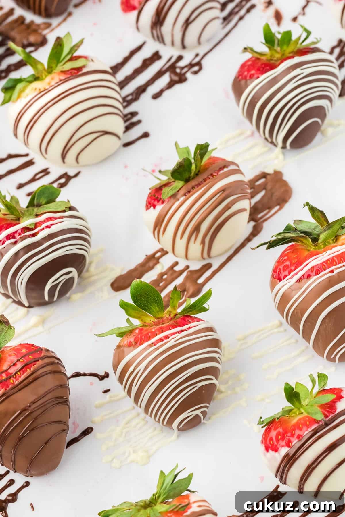 chocolate covered strawberries in rows, alternating white chocolate with a dark chocolate drizzle and milk chocolate with white and dark chocolate drizzles