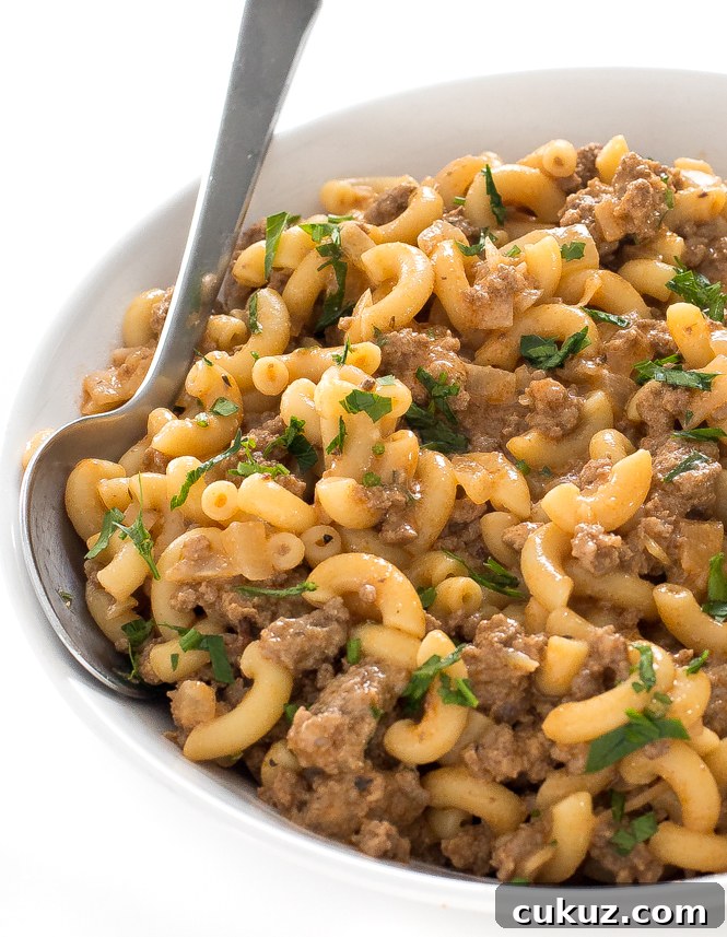Homemade hamburger helper in white bowl with spoon.