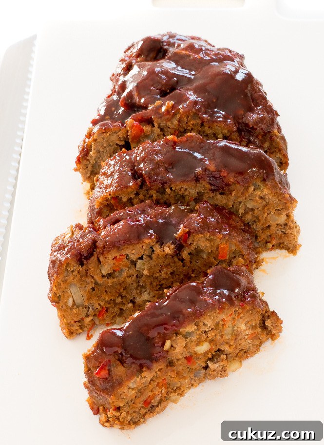 Easy Beef Meatloaf recipe on a white serving dish. Smothered in delicious BBQ sauce.