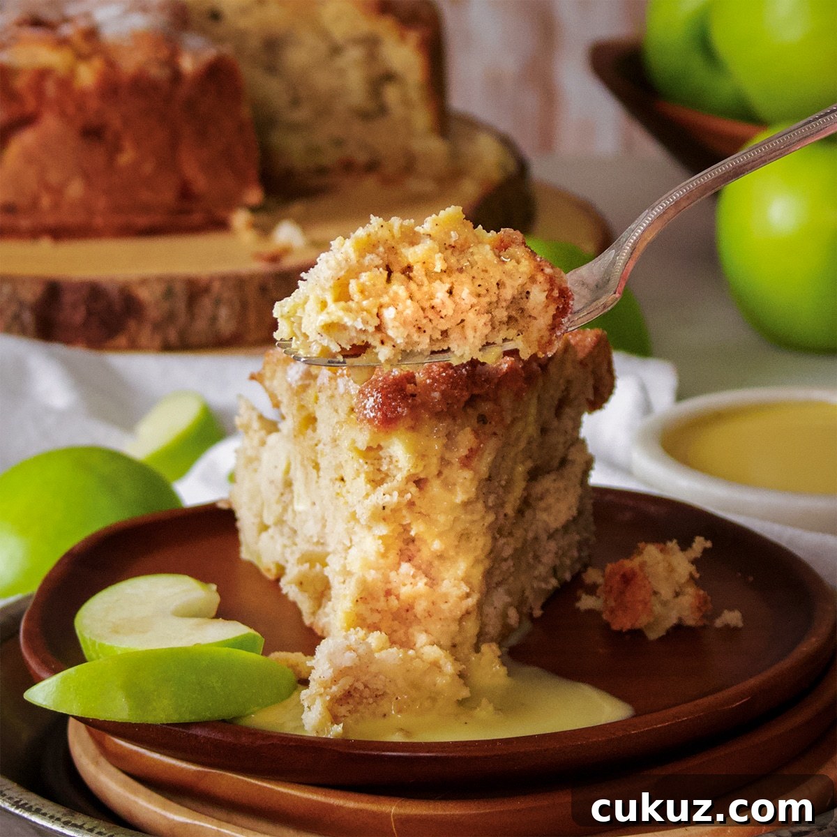 Someone using a fork to cut a bite of Irish Apple Cake from a slice on a wood plate.