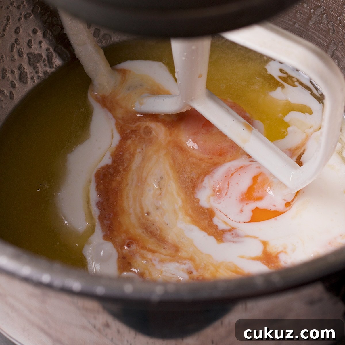 Using an electric mixer to beat egg yolks, buttermilk, and vanilla into butter and sugar.