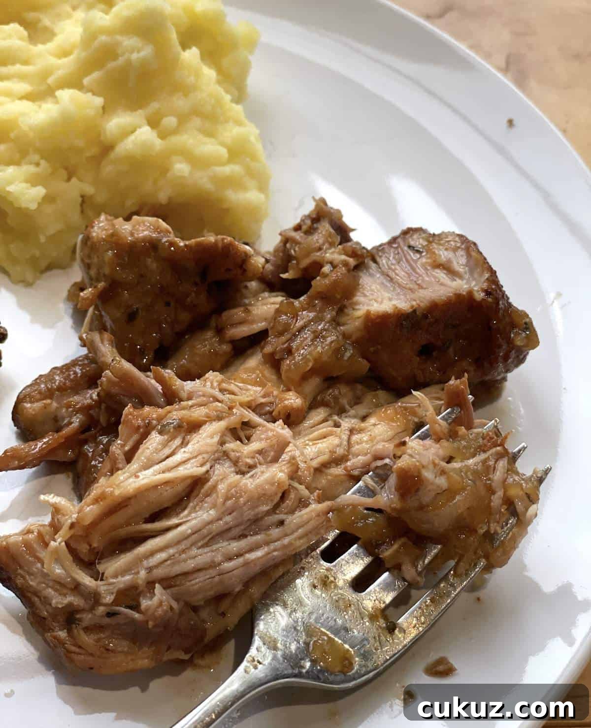 Instant Pot Country-Style Ribs with Tender, Fall-Off-the-Bone Results 8 A white plate with shredded country style ribs and a scoop of buttermilk mashed potatoes with a fork.