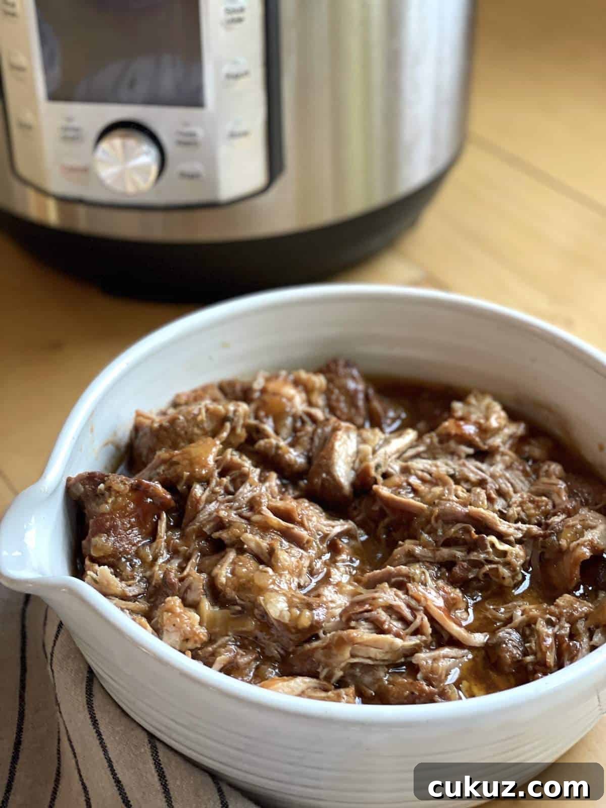 Instant Pot Country-Style Ribs with Tender, Fall-Off-the-Bone Results 4 A white bowl of Instant Pot country style ribs in front of an Instant Pot.