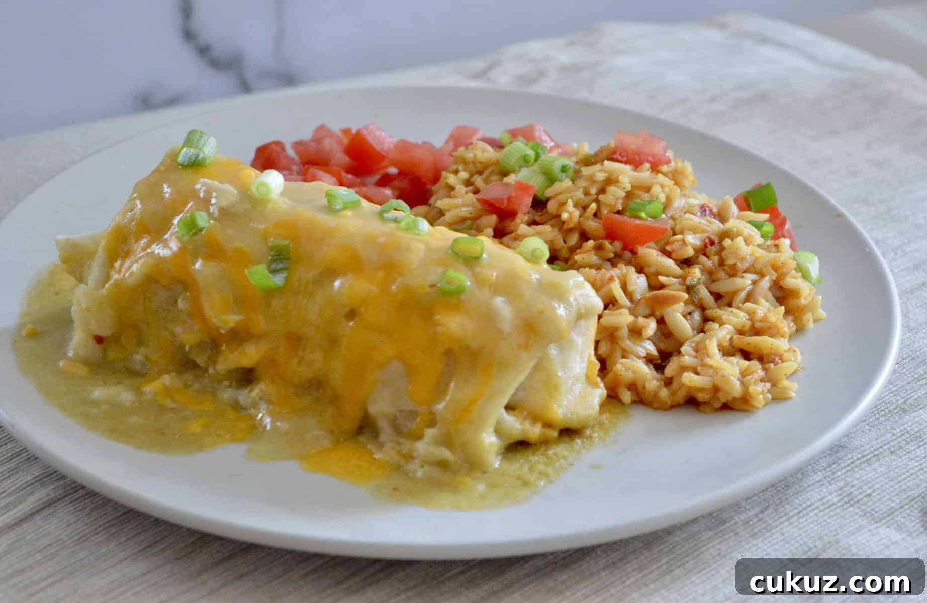 Green Chili Chicken Burritos on a white plate with mexican rice.