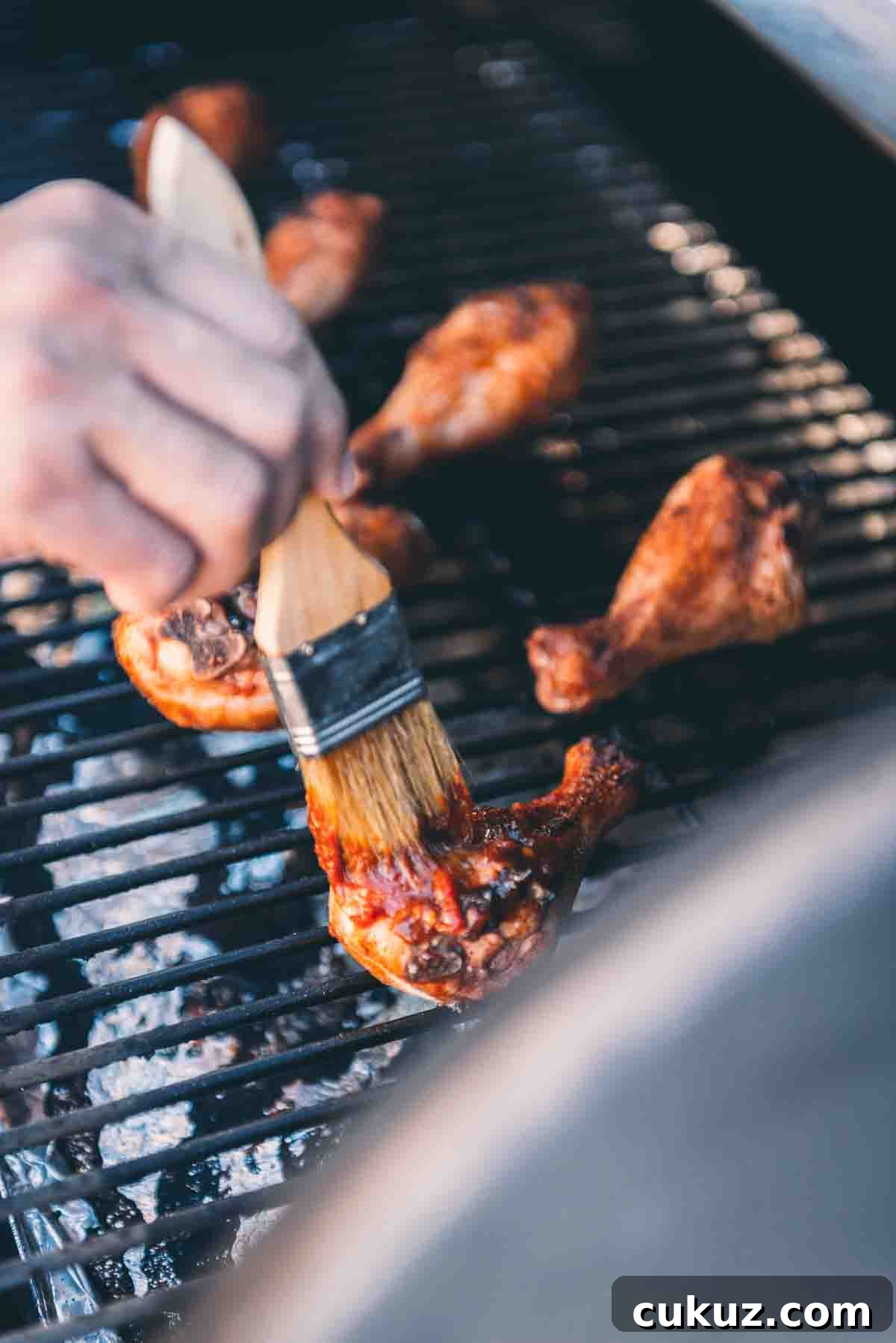Brush basting chicken with bbq sauce.