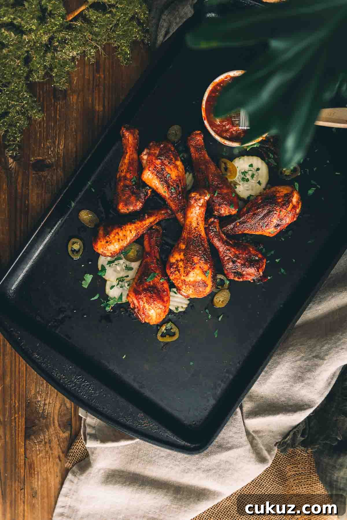 Overhead shot of smoked chicken legs piled onto a serving platter.