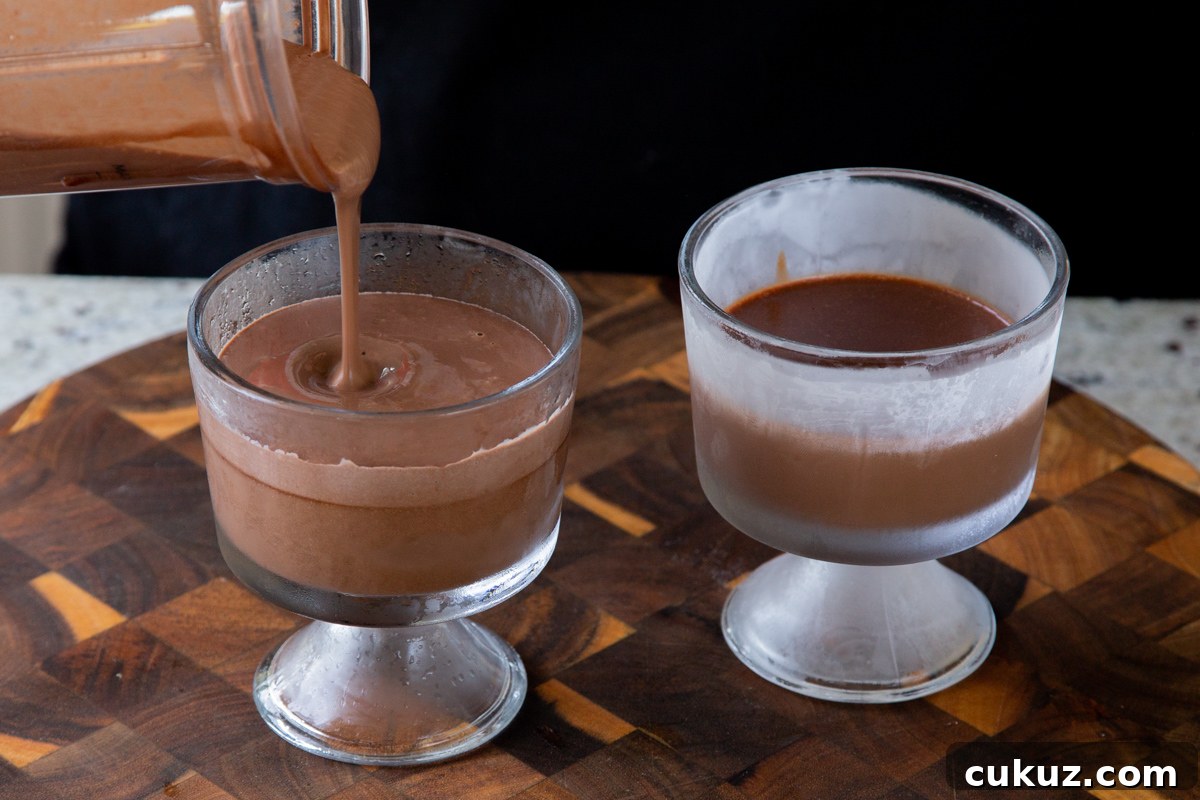 pouring mousse over the dark chocolate mixture in cups