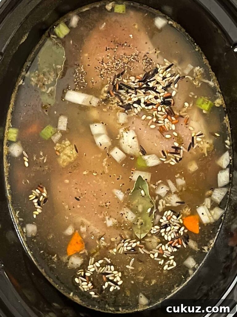 Slow cooker chicken and wild rice soup ingredients in the crock of a slow cooker.