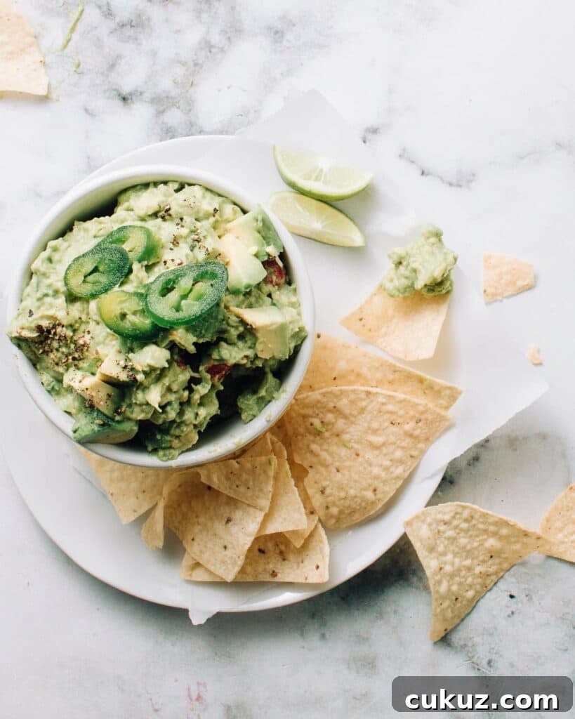 Authentic mexican guacamole in a bowl with jalapenos on top.